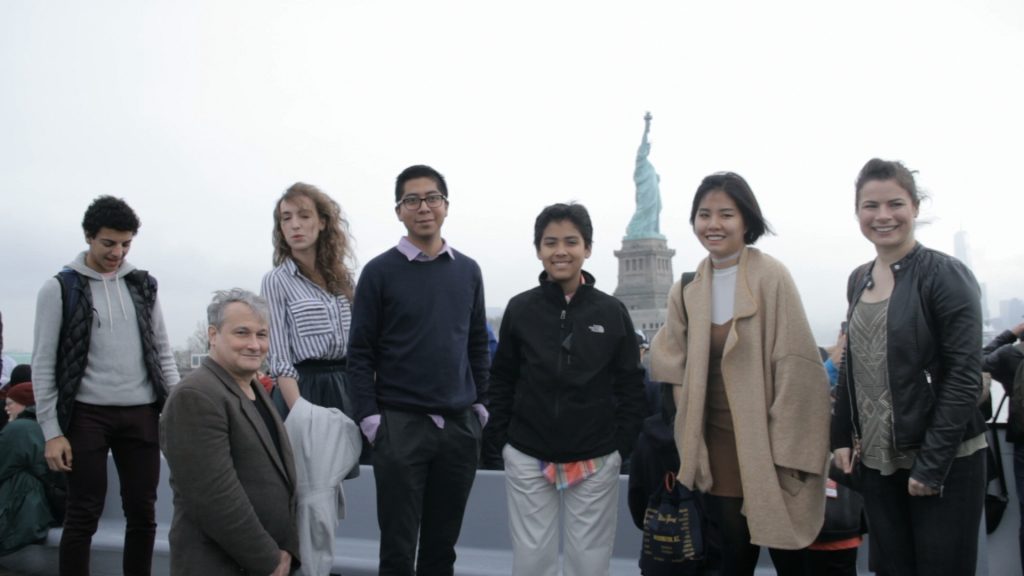 six young musicians and Christopher O'Riley with the statue of liberty in the background
